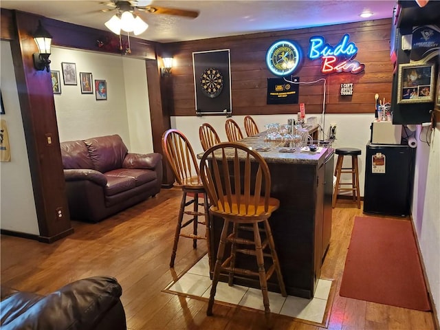 bar featuring ceiling fan and light hardwood / wood-style flooring