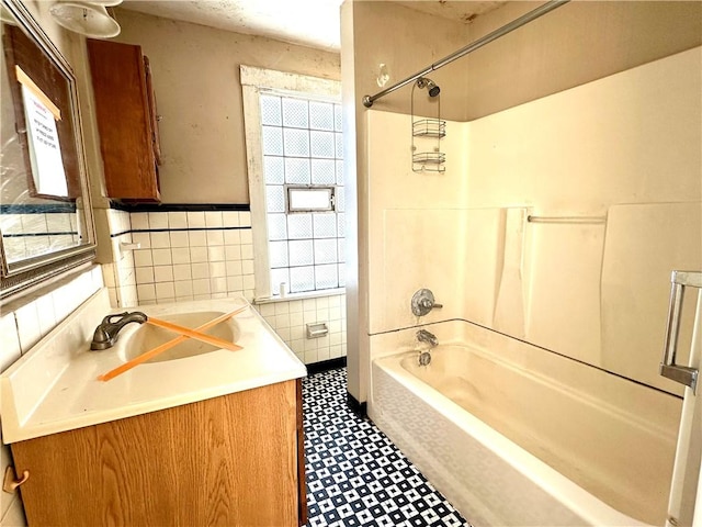 bathroom with vanity, shower / bath combination, and tile walls