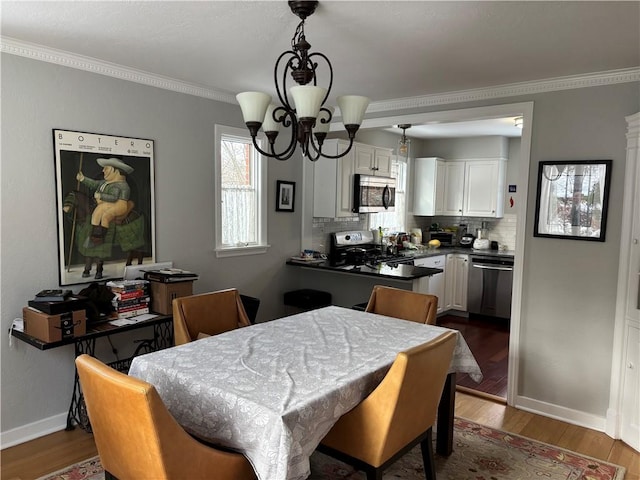 dining area featuring ornamental molding, dark wood-type flooring, and an inviting chandelier