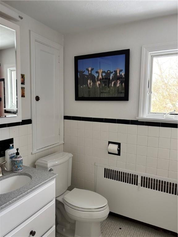 bathroom featuring tile walls, toilet, vanity, and radiator