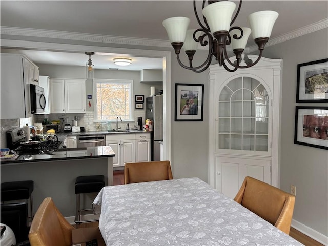 dining space featuring a notable chandelier, dark wood-type flooring, crown molding, and sink