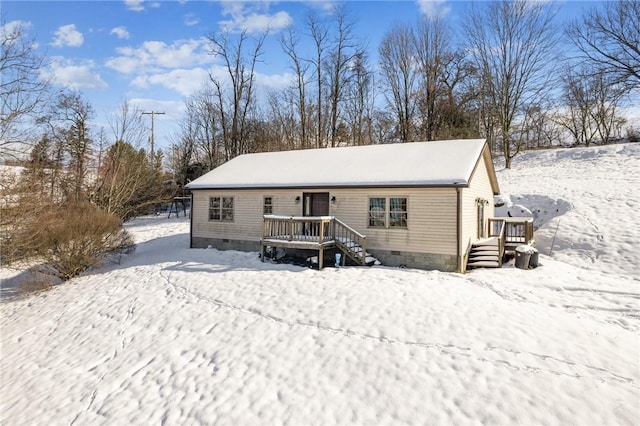 snow covered back of property with a wooden deck