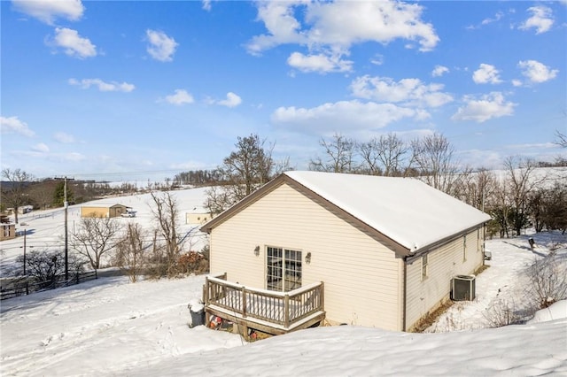 snow covered rear of property with central air condition unit and a wooden deck