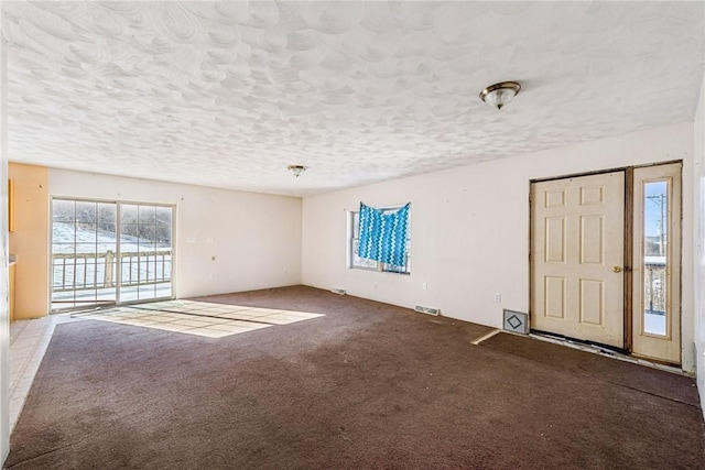 unfurnished living room featuring a textured ceiling and carpet floors