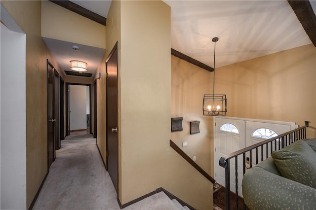 carpeted foyer entrance featuring lofted ceiling with beams and a notable chandelier