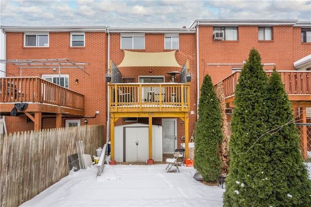 snow covered house featuring a deck and a storage unit