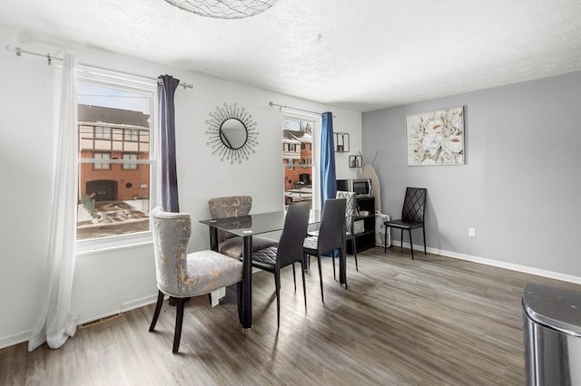 dining space with dark hardwood / wood-style floors and a textured ceiling