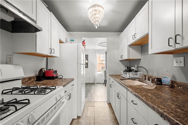 kitchen with dark stone counters, gas range gas stove, sink, an inviting chandelier, and white cabinets