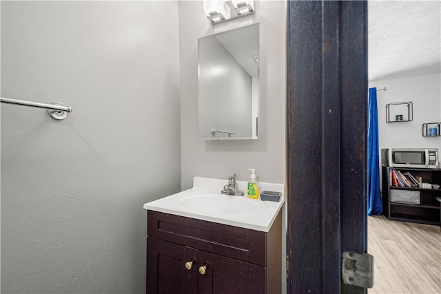 bathroom featuring vanity, wood-type flooring, and a textured ceiling