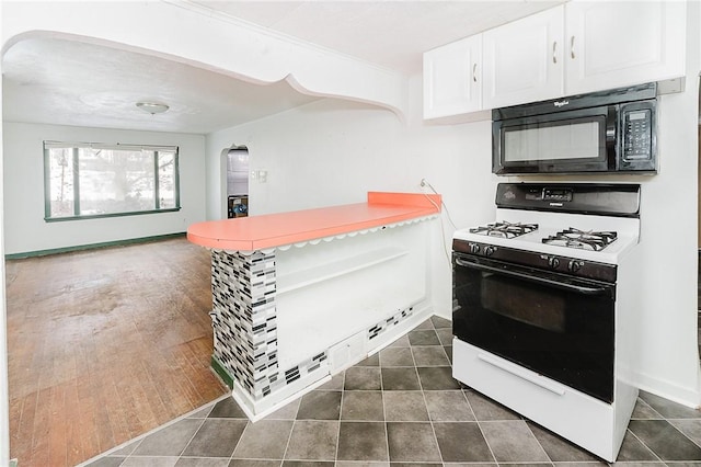 kitchen with gas range, white cabinets, and dark tile patterned flooring