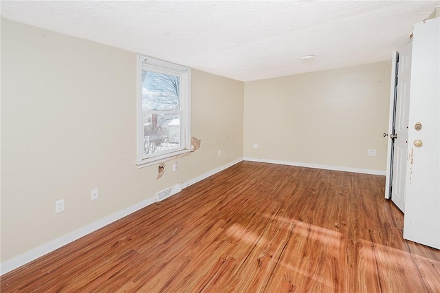 empty room with a textured ceiling and light hardwood / wood-style floors