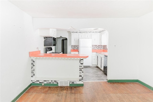 kitchen featuring backsplash, a breakfast bar, black dishwasher, white fridge, and white cabinetry