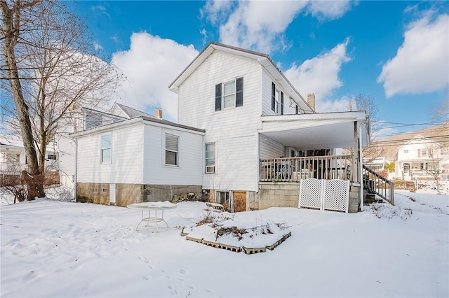 snow covered back of property with a porch