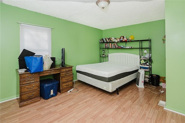 bedroom with a textured ceiling and light hardwood / wood-style floors