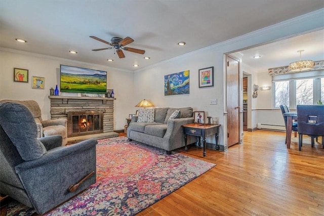 living room with crown molding, light hardwood / wood-style flooring, ceiling fan, a fireplace, and a baseboard radiator