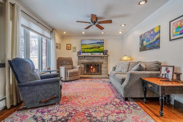 living room with ceiling fan, a fireplace, wood-type flooring, and ornamental molding