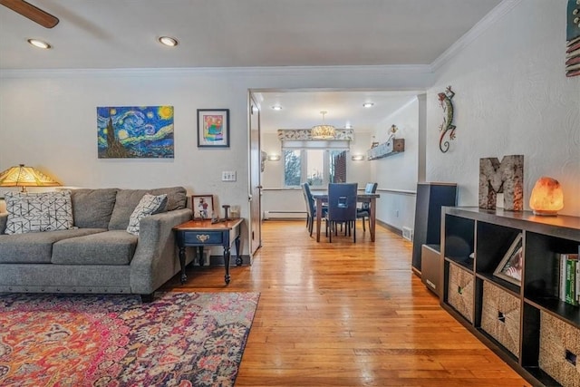 living room with a baseboard heating unit, hardwood / wood-style flooring, ceiling fan, and ornamental molding