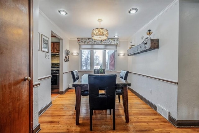 dining area with light wood-type flooring and ornamental molding