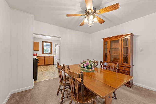 carpeted dining room with ceiling fan and sink