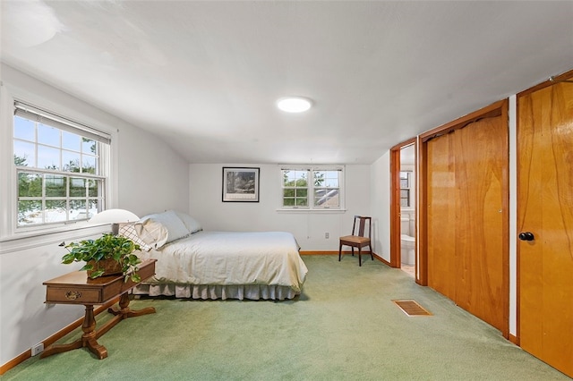 carpeted bedroom featuring multiple windows, lofted ceiling, and two closets