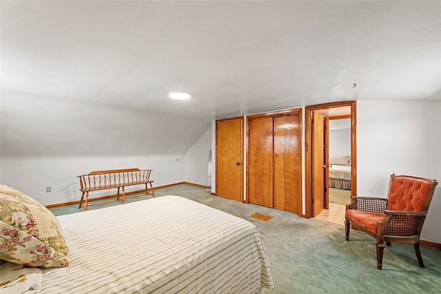 carpeted bedroom with lofted ceiling and connected bathroom