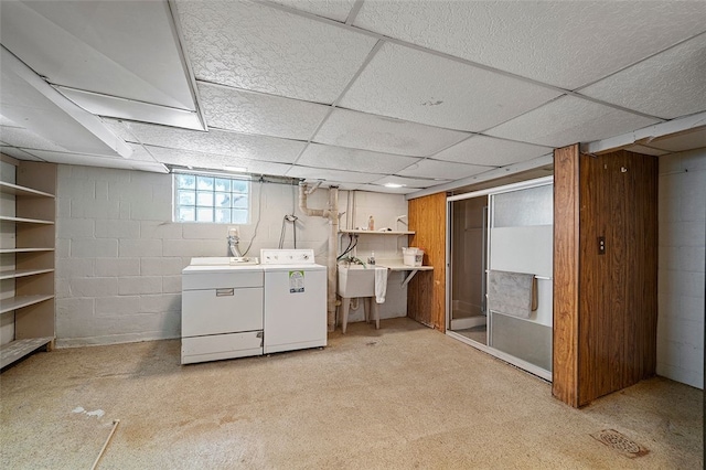 basement featuring a paneled ceiling, washer and clothes dryer, and sink