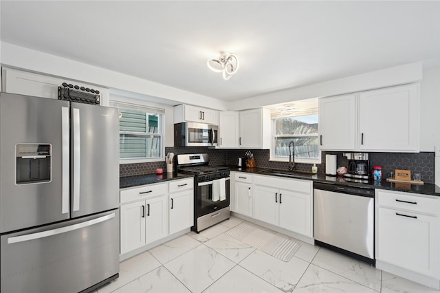 kitchen with stainless steel appliances, white cabinetry, a healthy amount of sunlight, and sink