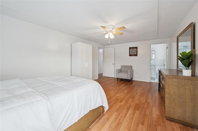 bedroom with ensuite bath, ceiling fan, and light hardwood / wood-style flooring