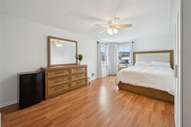 bedroom with ceiling fan, light hardwood / wood-style flooring, and refrigerator