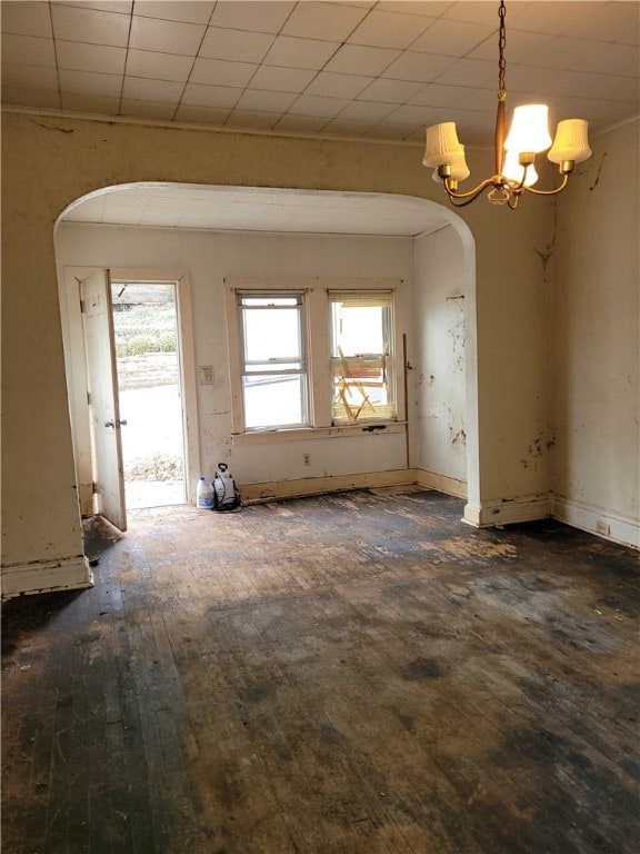 spare room featuring a chandelier, a wealth of natural light, and dark hardwood / wood-style floors