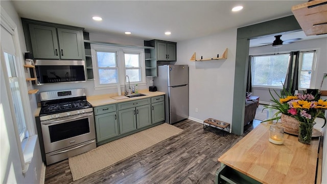 kitchen featuring dark wood-type flooring, green cabinetry, appliances with stainless steel finishes, ceiling fan, and sink