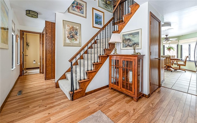 stairway featuring ceiling fan and hardwood / wood-style flooring