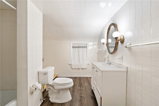 bathroom featuring tile walls, toilet, wood-type flooring, and vanity