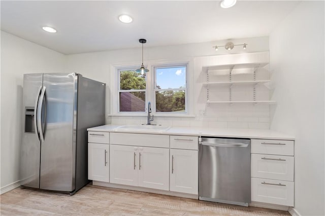 kitchen featuring sink, stainless steel appliances, white cabinetry, and pendant lighting