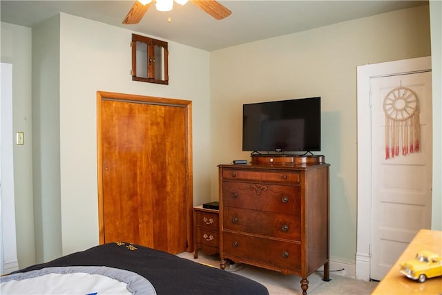 bedroom featuring light colored carpet, ceiling fan, and a closet