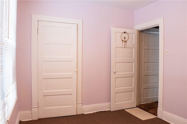 unfurnished bedroom with a closet and dark colored carpet