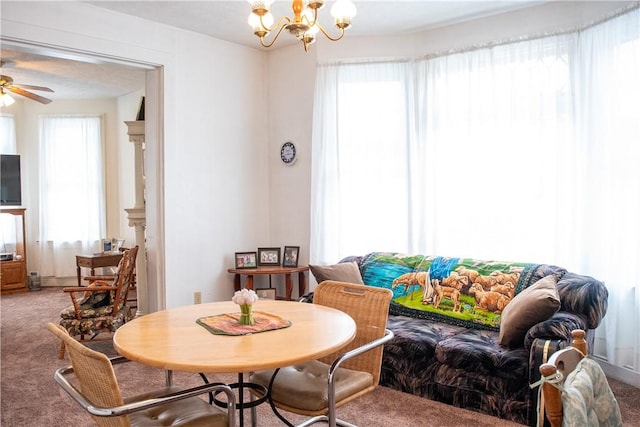 dining area with carpet and ceiling fan with notable chandelier