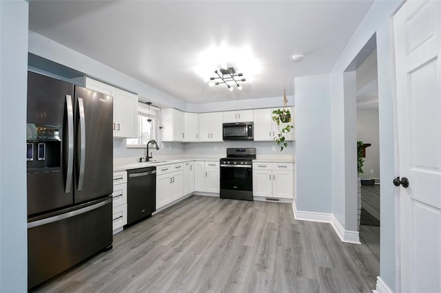 kitchen with light wood-type flooring, appliances with stainless steel finishes, sink, and white cabinetry