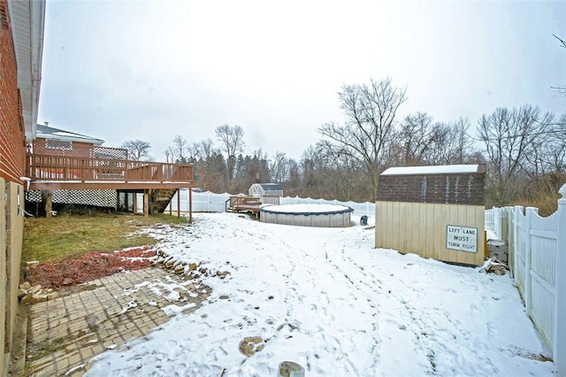 snowy yard with a swimming pool side deck and a storage unit