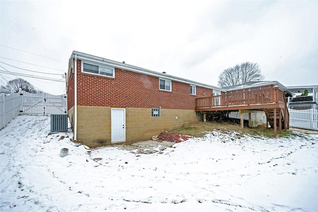 snow covered house with a wooden deck and central air condition unit