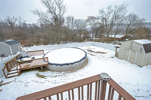 yard layered in snow featuring a storage unit and a wooden deck