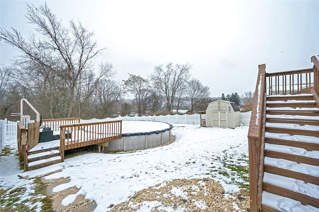 yard layered in snow featuring a pool side deck and a storage shed