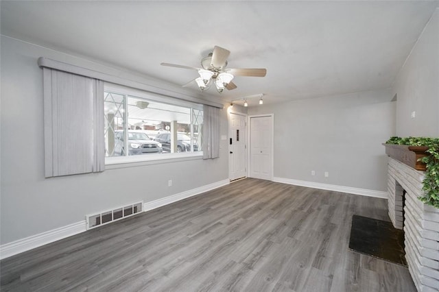 unfurnished living room with a brick fireplace, hardwood / wood-style flooring, and ceiling fan