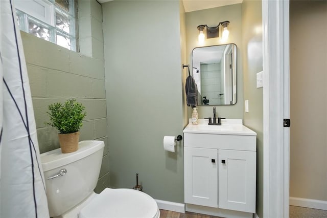 bathroom with toilet, vanity, and wood-type flooring