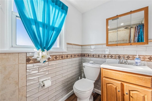 bathroom with toilet, vanity, and tile walls