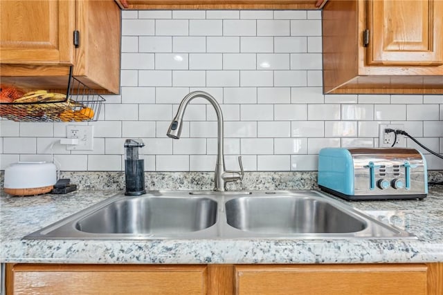 details featuring sink, decorative backsplash, and light stone countertops