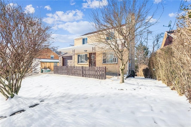 snow covered rear of property with a garage