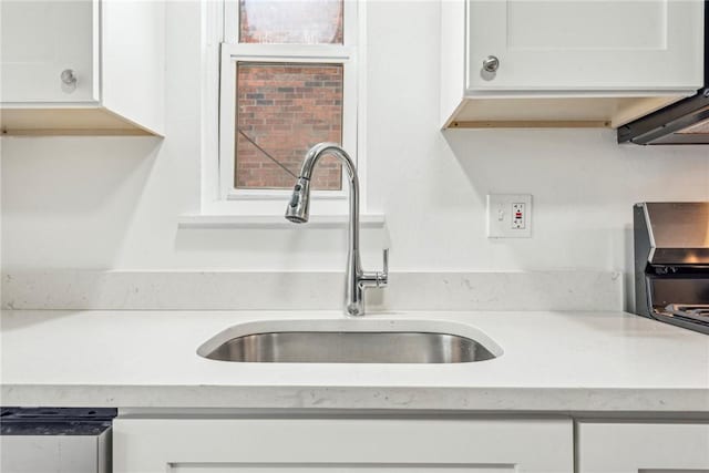 kitchen featuring sink, white cabinetry, and range