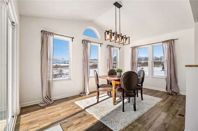 dining space with vaulted ceiling, a notable chandelier, and wood-type flooring