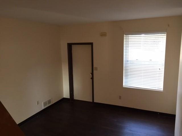 empty room featuring dark wood-type flooring and visible vents